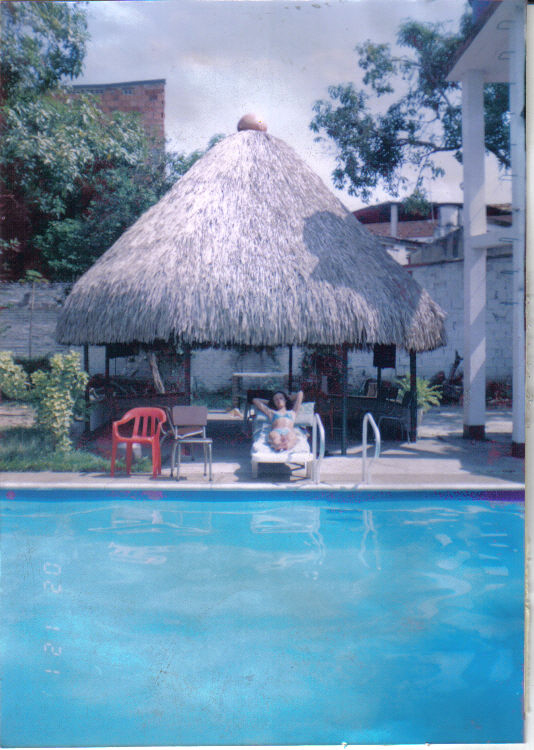 Persona tomando el sol junto a la piscina debajo de un bungalow